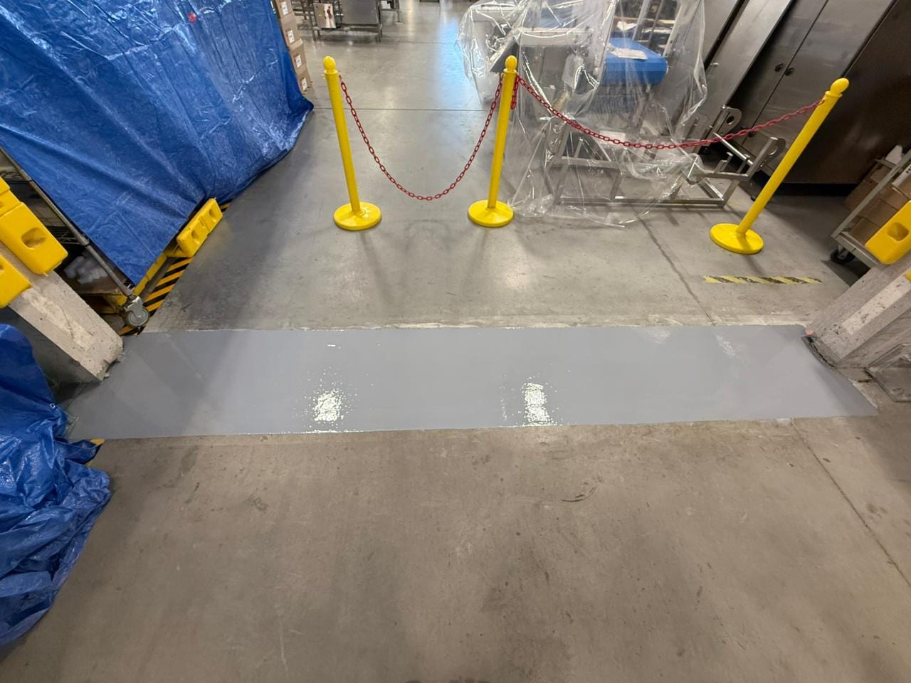 Glossy grey epoxy floor coating freshly applied on a commercial warehouse floor