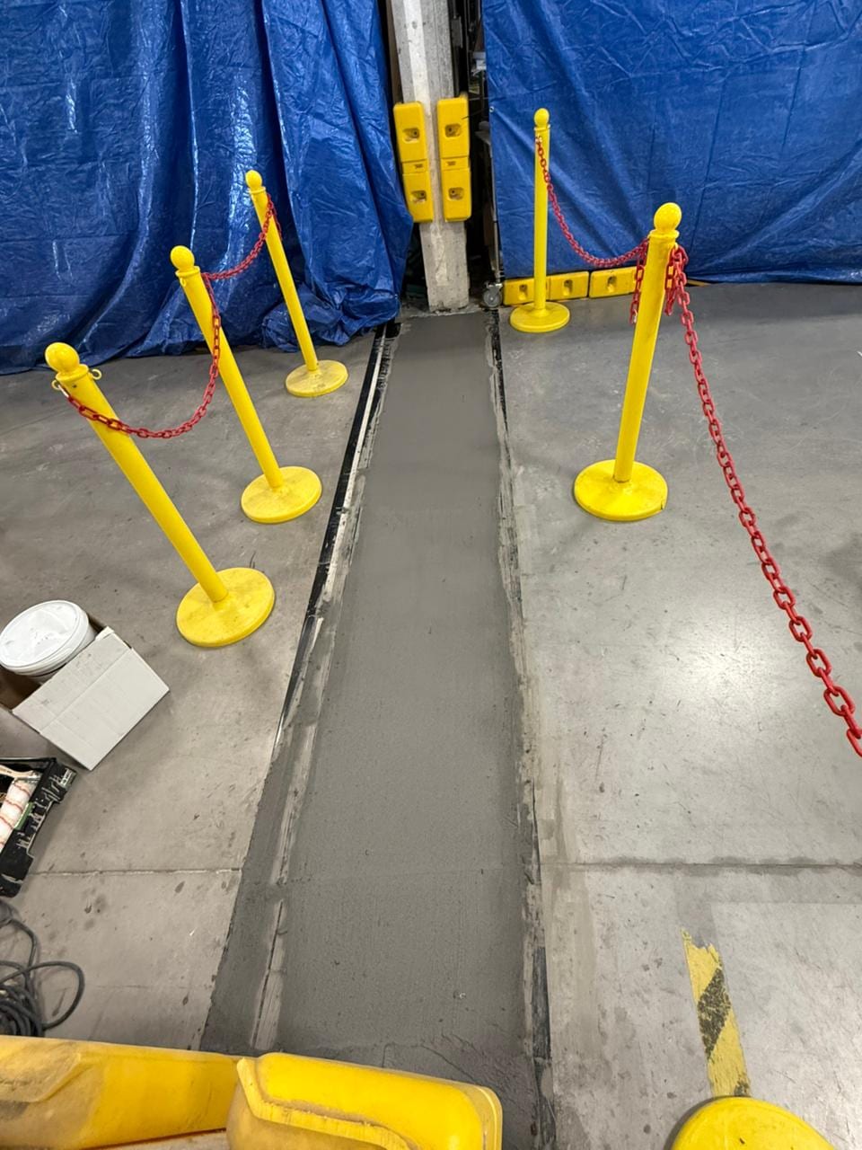 A commercial concrete floor joint repaired with traffic-rated material and cordoned to cure