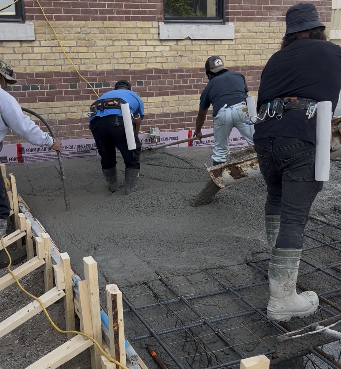 The crew screeding a fresh pour over a tied rebar mat