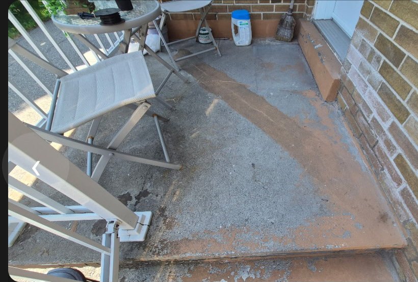 A weathered porch floor with pale mineral deposits and rust staining across the surface