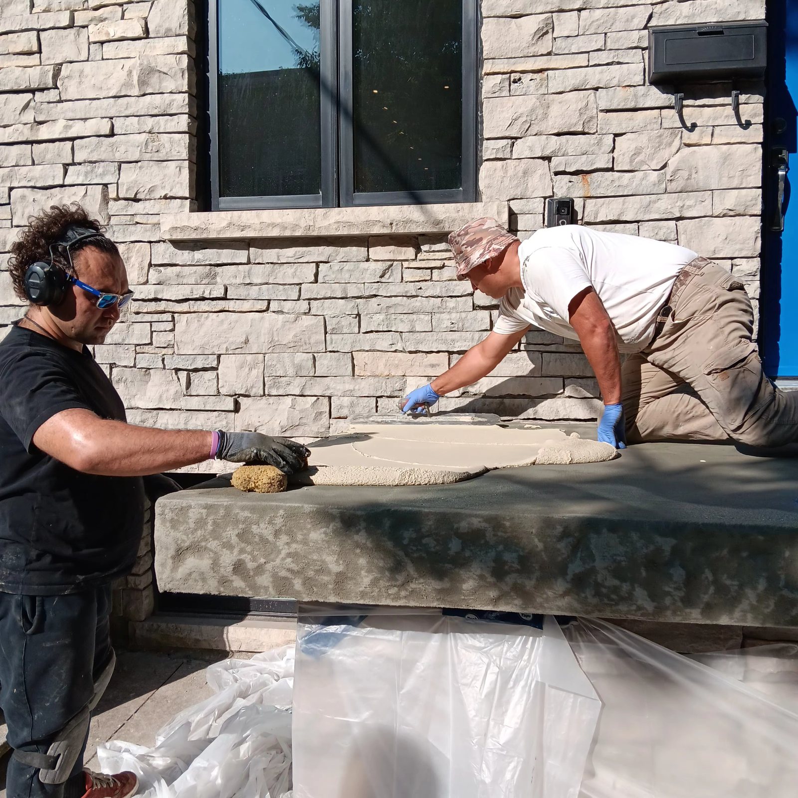 Two crew members hand-trowelling a cementitious overlay across a porch slab